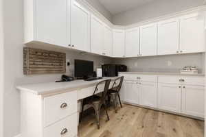 Home office with built in desk and light hardwood / wood-style floors