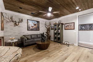 Living room with crown molding, brick wall, wooden ceiling, and light hardwood / wood-style floors