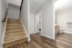 Stairway with hardwood / wood-style flooring and lofted ceiling