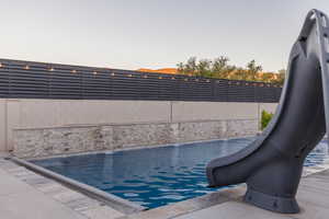 Pool at dusk featuring pool water feature