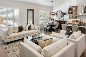 Living room featuring vaulted ceiling, a chandelier, and light hardwood / wood-style flooring