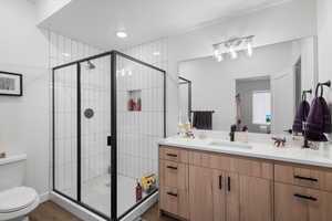 Bathroom with vanity, toilet, an enclosed shower, and wood-type flooring