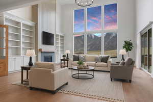 Living area with a high ceiling, a glass covered fireplace, light wood-type flooring, and built in shelves
