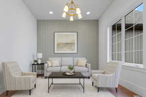 Living area with wood finished floors, a chandelier, wooden walls, and recessed lighting