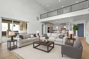 Living area with light wood-style flooring, a towering ceiling, and recessed lighting