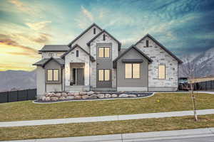 View of front of home with a mountain view and a lawn