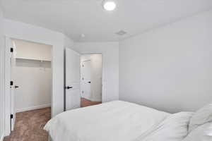 Bedroom featuring a walk in closet, dark carpet, and a closet