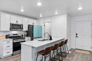 Kitchen with a breakfast bar, sink, white cabinets, kitchen peninsula, and stainless steel appliances