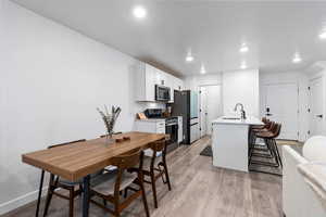 Kitchen with sink, white cabinetry, a kitchen breakfast bar, stainless steel appliances, and a kitchen island with sink