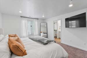 Carpeted bedroom with connected bathroom and a textured ceiling