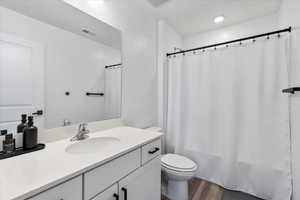 Full bathroom featuring vanity, hardwood / wood-style flooring, toilet, and shower / tub combo with curtain