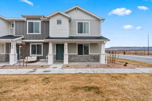 View of front of home with a porch, a mountain view, and a front lawn