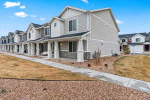 View of front of house with cooling unit, a front lawn, and covered porch