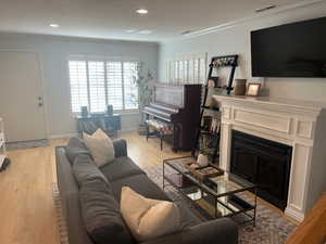 Living room featuring ornamental molding and light hardwood / wood-style floors