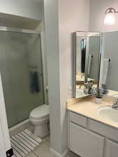 Bathroom with tile patterned flooring, vanity, toilet, and walk in shower