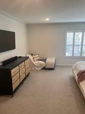 Carpeted bedroom featuring crown molding