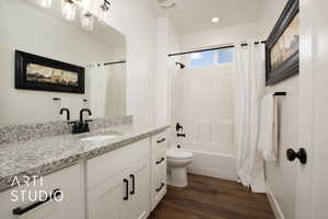 Full bathroom with vanity, toilet, hardwood / wood-style floors, and shower / bath combo