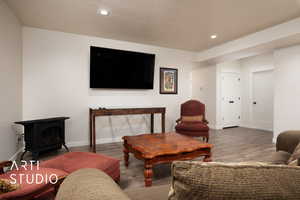 Living room with wood-type flooring, a textured ceiling, and a wood stove