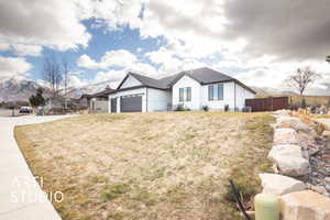 View of front of property featuring a garage, a mountain view, and a front yard