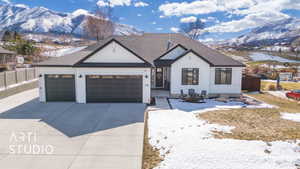 View of front of house with driveway, an attached garage, fence, and a mountain view