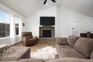 Living room featuring ceiling fan, high vaulted ceiling, light wood-type flooring, and a fireplace