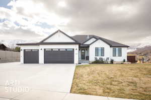 View of front of property featuring a garage, a mountain view, and a front lawn