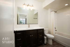 Full bathroom with wood-type flooring, toilet, shower / bath combo with shower curtain, and vanity