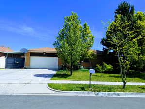 View of front of property with fence, concrete driveway, a front lawn, and a garage