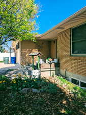 View of property exterior featuring brick siding, a garage, and fence