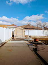 Exterior space featuring a patio, a shed, an outdoor structure, and a fenced backyard