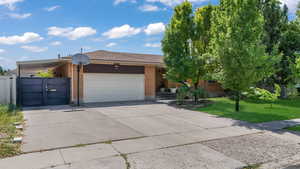 View of front of house with brick siding, concrete driveway, a garage, and a gate