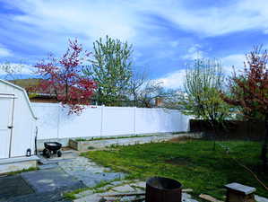 View of yard featuring a fenced backyard, an outbuilding, a patio, and a storage shed