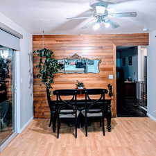 Dining area with hardwood / wood-style flooring, wood walls, and a textured ceiling