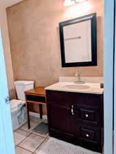Bathroom with toilet, vanity, and tile patterned flooring