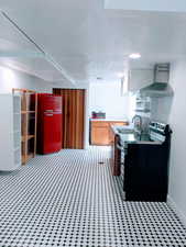 Kitchen with wall chimney range hood, electric range, and sink