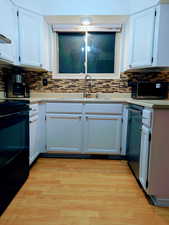 Kitchen with appliances with stainless steel finishes, tasteful backsplash, and white cabinetry