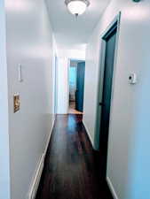 Hallway with dark hardwood / wood-style flooring and a baseboard heating unit