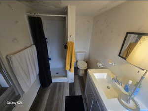 Bathroom with toilet, a textured ceiling, vanity, curtained shower, and hardwood / wood-style floors