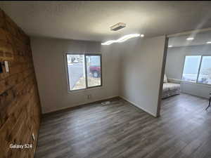 Empty room with dark hardwood / wood-style flooring and a textured ceiling