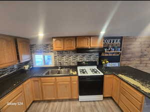 Kitchen with tasteful backsplash, range with gas stovetop, sink, and light wood-type flooring