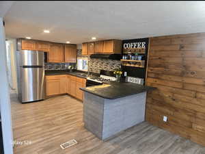 Kitchen with gas range, sink, stainless steel refrigerator, and light hardwood / wood-style flooring