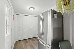 Kitchen featuring hardwood / wood-style flooring, stainless steel fridge, and a textured ceiling