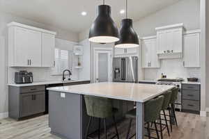 Kitchen featuring high quality appliances, a center island, sink, and gray cabinetry