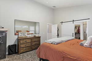 Bedroom featuring a walk in closet, carpet floors, a closet, a barn door, and a high ceiling