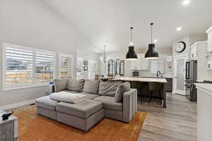 Living room featuring high vaulted ceiling, sink, and light hardwood / wood-style floors