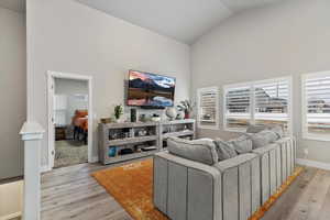 Living room with light wood-type flooring and high vaulted ceiling