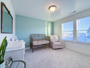 Bedroom featuring carpet floors, a textured ceiling, and a crib