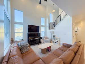 Living room featuring a towering ceiling, light colored carpet, and ceiling fan