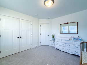 Bedroom with light carpet, a textured ceiling, and a closet