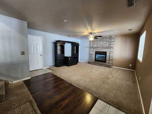 Unfurnished living room with a brick fireplace, light hardwood / wood-style flooring, and ceiling fan